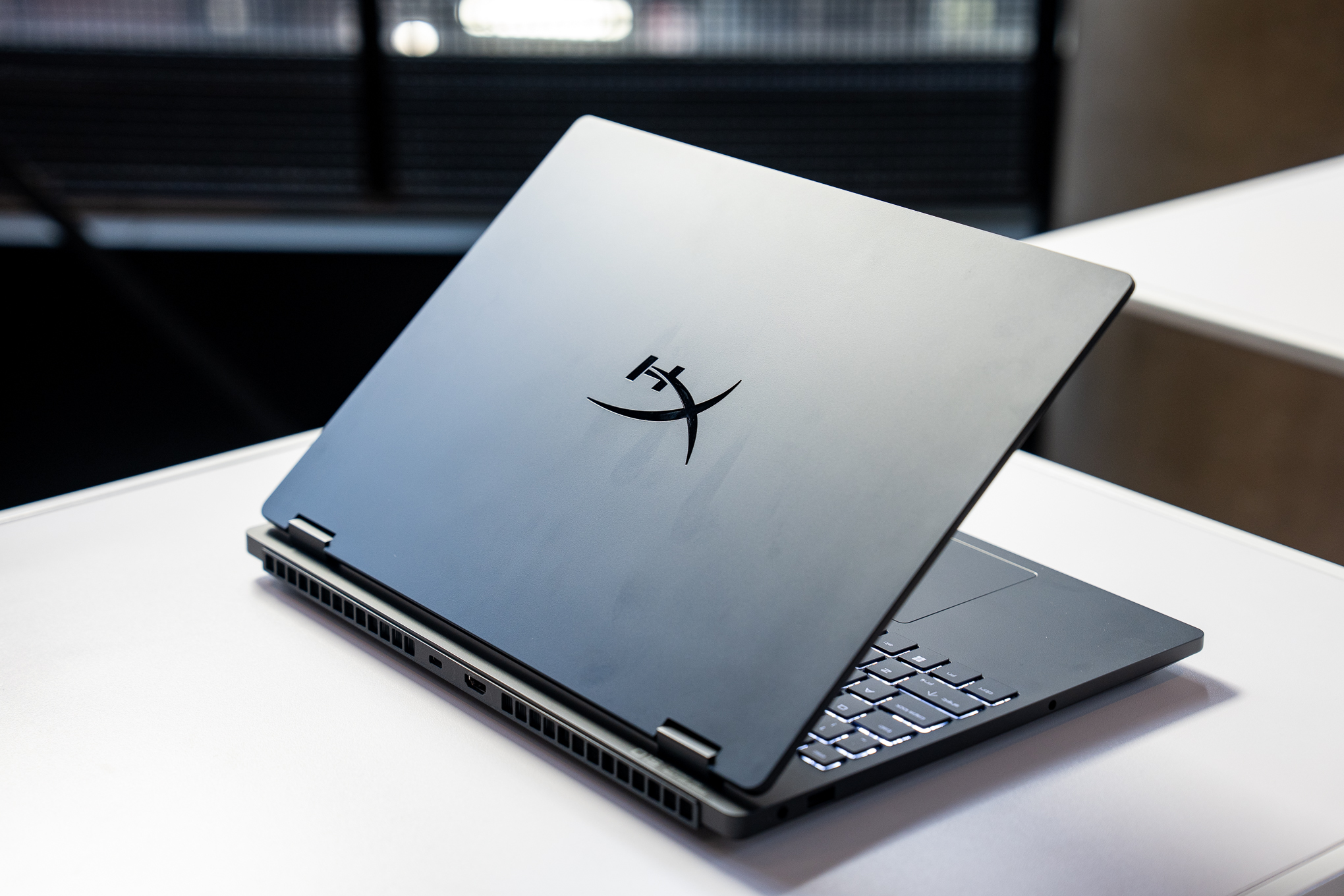 HP Omen 15 gaming laptop sitting on a white table from a rear three-quarter view.