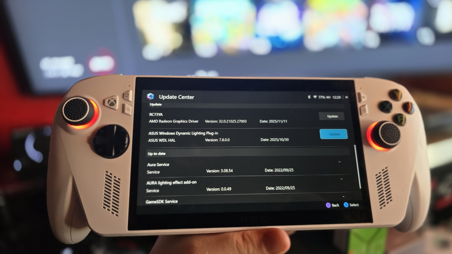 A handheld gaming device displays an update center screen for various services. The room is dimly lit, creating an immersive gaming atmosphere.