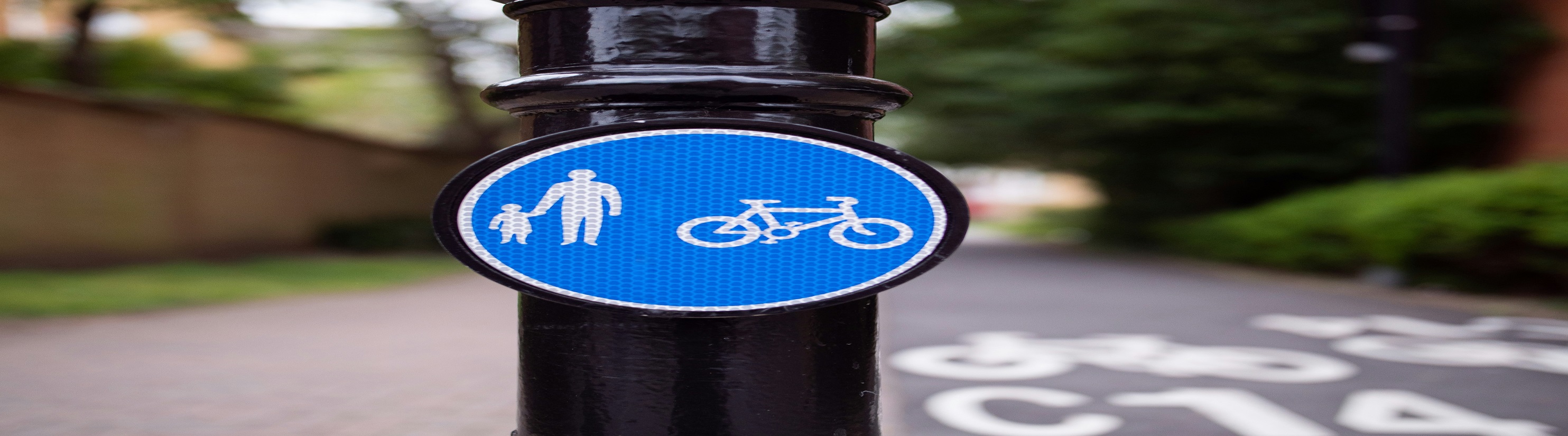 Photo of black bollard with blue & white shared-use path sign