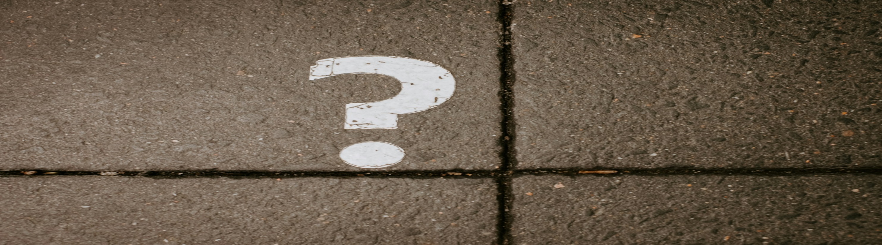 Photo of white question mark painted onto paved surface.