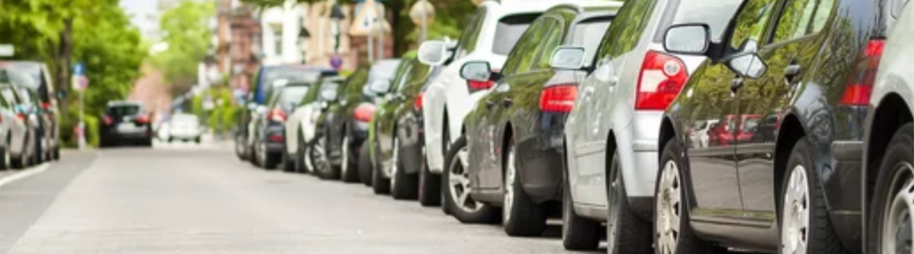 Photo of cars parked on right hand side of road.