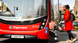 Lady getting on a bus with a pram.