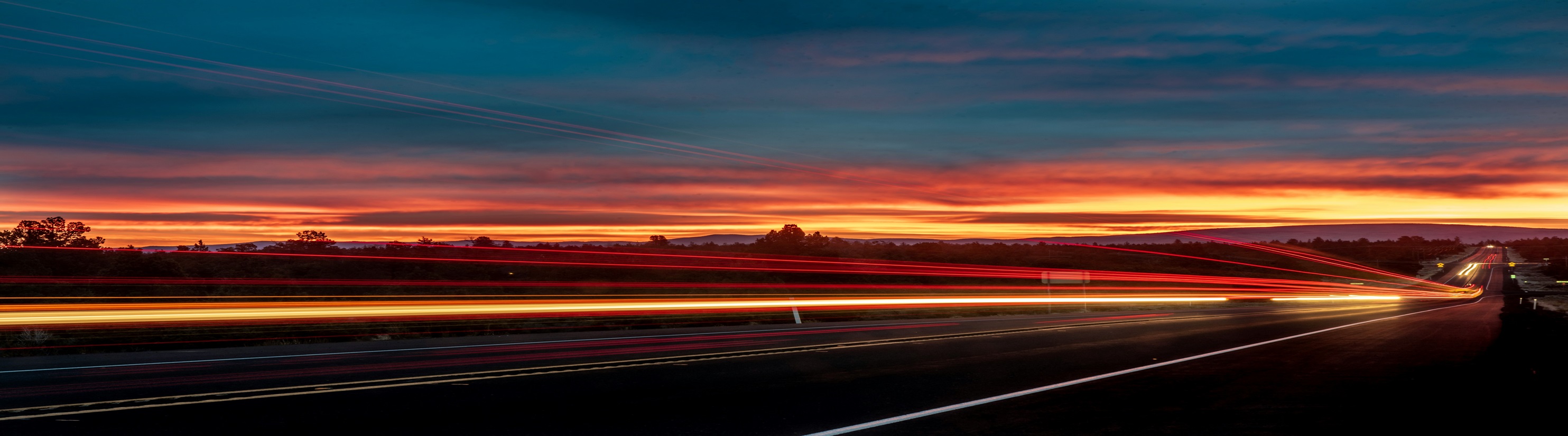 Photo of red sky at night and lights from vehicle traffic.