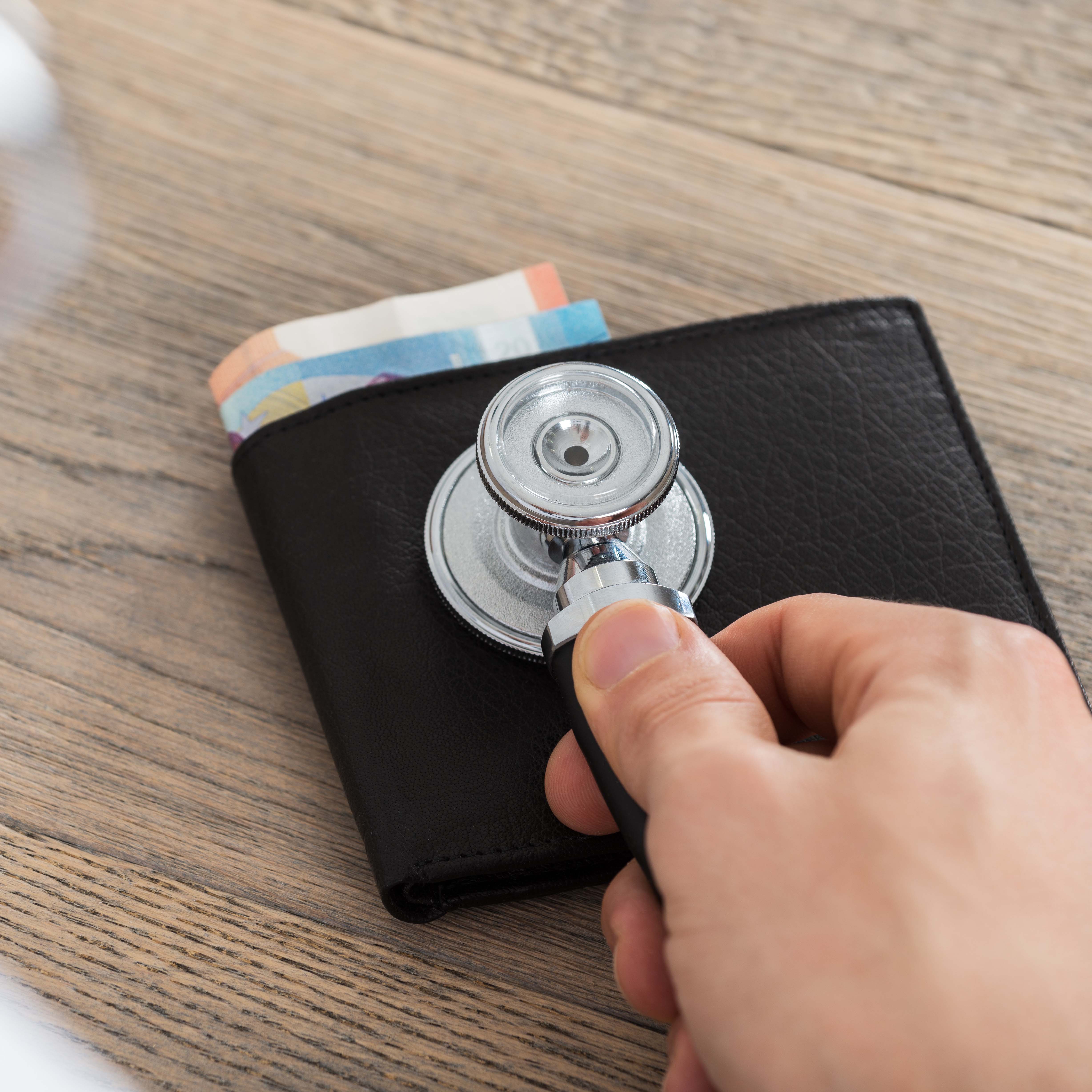 Hand hört mit Stethoskop Portemonnaie ab