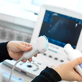 Hände mit Schallkopf vor Sonographiegerät