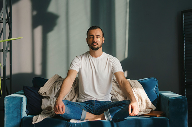 Mann auf dem Sofa macht Atemübung