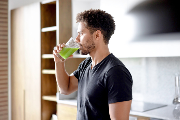 Mann trinkt grünen Smoothie