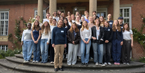 Eine Gruppe von Jugendlichen posiert zusammen mit Veronika Nahm auf einer Steintreppe.