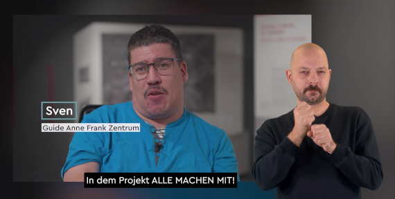 Mann spricht in einer Ausstellung, eingeblendet sind sein Name „Sven“ und die Bezeichnung „Guide Anne Frank Zentrum“, rechts daneben ist ein Gebärdensprachdolmetscher zu sehen.