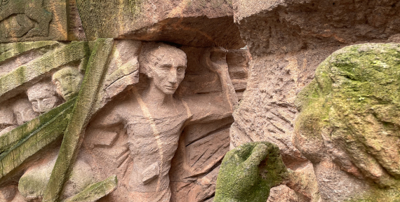Steinernes Relief mit einer menschlichen Figur, die aus dem Fels herausgearbeitet ist.