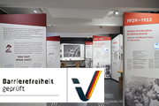 Mehrere Ausstellungswände, links unten der Schriftzug Barrierefreiheit geprüft