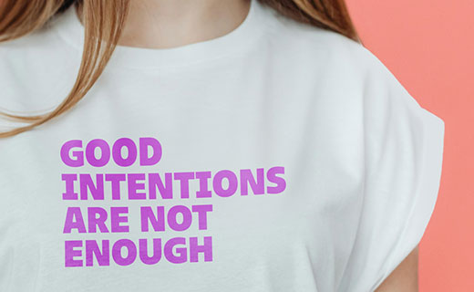 Eine Frau trägt ein T-Shirt mit der Aufschrit "Good intentions are not good enough"