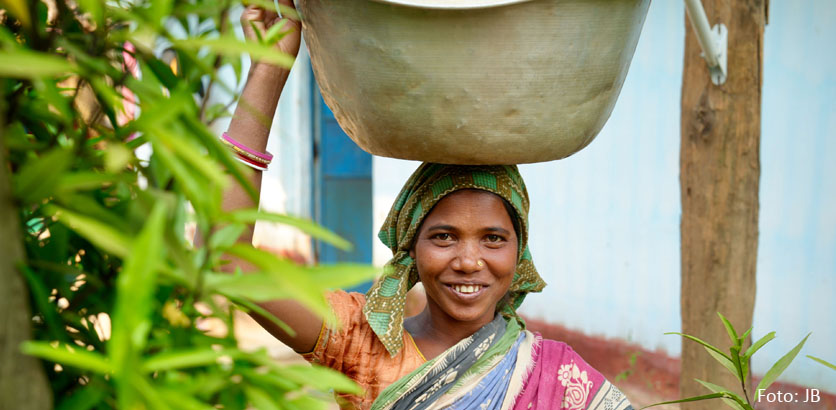 Eine indische Frau trägt eine Schüssel Wasser auf dem Kopf