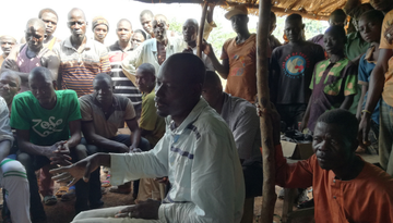 Eine Gruppe Menschen, hauptsächlich Männer, sitzt beisammen