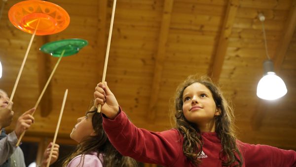 Auf dem Bild sieht man Kinder, die Teller auf Stöcken balancieren.