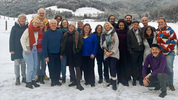 20 Seminarteilnehmende posieren im Schnee vor schneebedeckten Bergen.