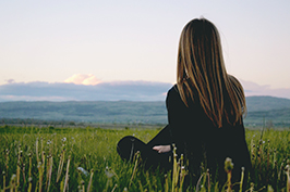 Frau sitzend auf der Wiese | Pexels/Jure Širić