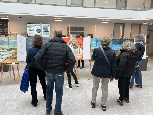 Menschen betrachten Bilder auf Staffeleien