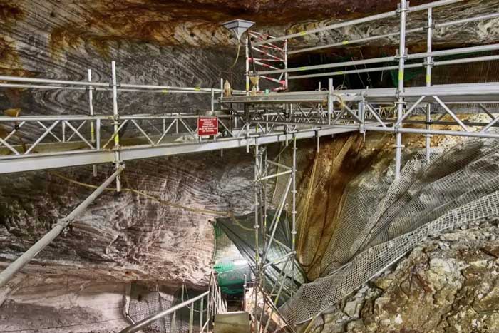 Blick in ein Bergwerk. In einem Hohlraum unter Tage sind mehrere Baugerüste aufgebaut.