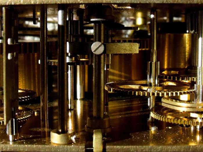 Detailaufnahme eines goldenen Uhrwerks mit Schrauben und Zahnrädern.