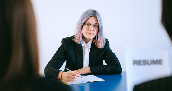Eine junge Frau mit gefärbtem Haar macht Notizen während eines Vorstellungsgesprächs.