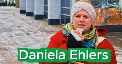 Daniela Ehlers mit einem Mikrofon in der Hand vor einem Haus stehend