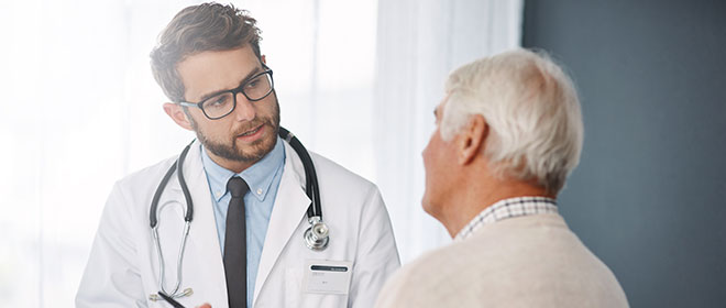 Junger Arzt ist im Gespräch mit älterem Patienten