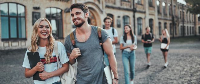 Junge Ärztin sitzt in ihrer Praxis und hält lächelnd ein Tablet in der Hand