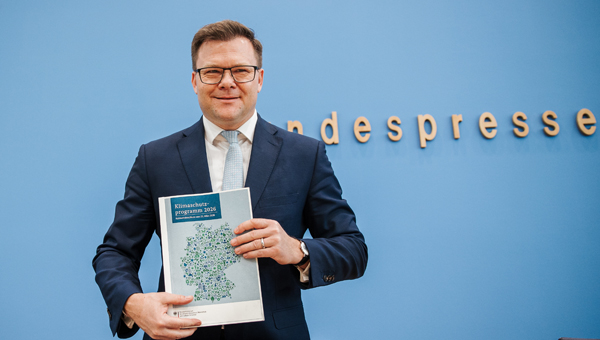 Carsten Schneider hält das Programm in die Kamera.