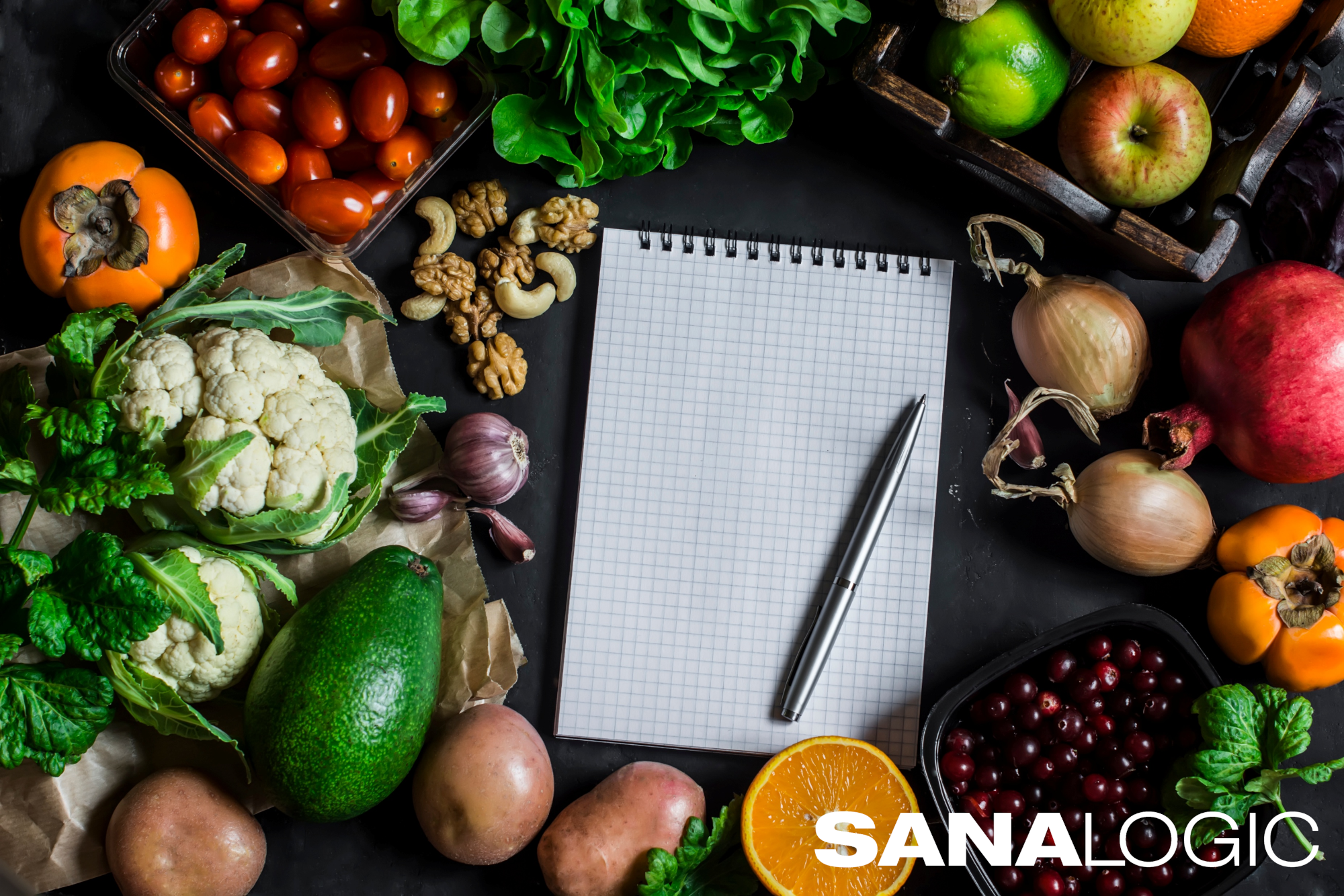 Tisch mit verschiedenem Gemüse, mittig ein Notizblock und Stift. Zusätzlich befindet sich unten rechts das Logo SANALOGIC.