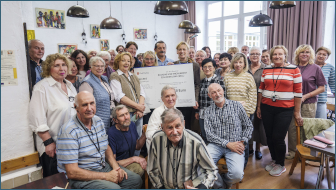 Das Bild zeigt eine Menschengruppe, in der Mitte hält die Bundesministerin für Bildung, Familie, Senioren, Frauen und Jugend, Karin Prien, eine symbolische BELL-Förderurkunde.