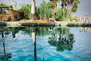 Bildungsurlaub Achtsam im Moment – Yoga und Fotografie erleben Die Kursleiterin praktiziert Yoga am Pool. Im Hintergrund sieht man die Finca und Palmen.