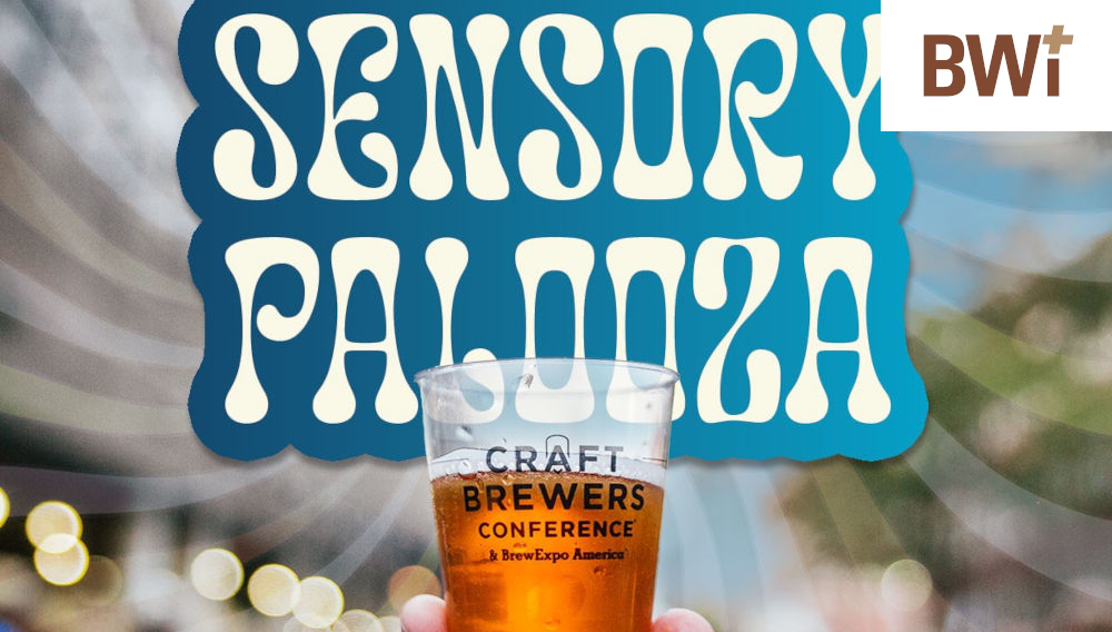Hand holding a Craft Brewers Conference tasing glass containing an amber liquid; in the background, a blue and white sign is integrated into the picture, which reads, “Sensory Palooza” in capital letters (Image courtesy of the Brewers Association)
