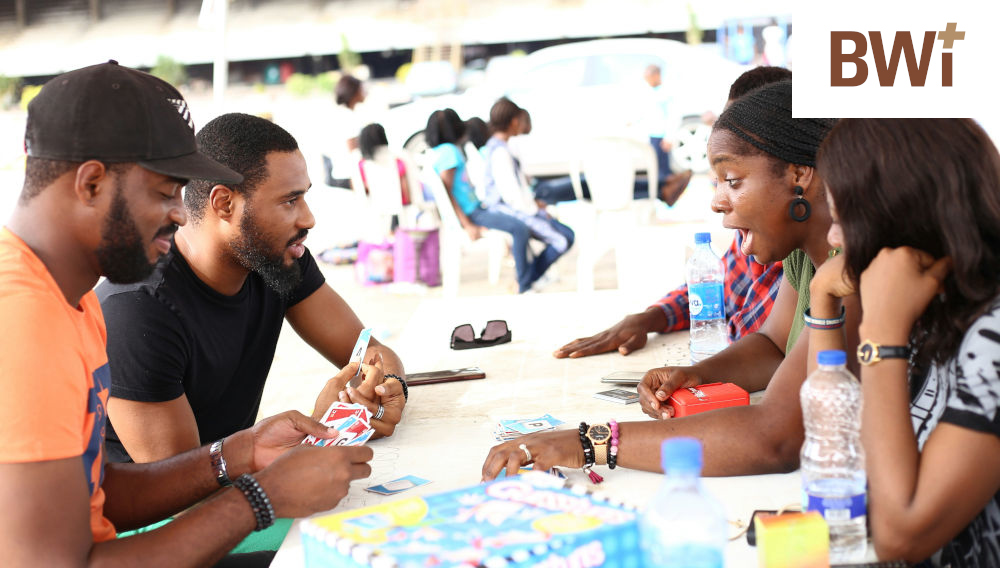 People stiing around a table with water bottles in front of them, talking lively with each other (Photo: Shina Memud on Unsplash)