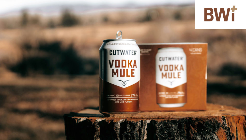 Close-up photo of a brown-and-white vodka mule can next to a vodka mule cardboard package, placed on a tree disc outside, against a blurry background (Photo: Glenna Haug on Unsplash)