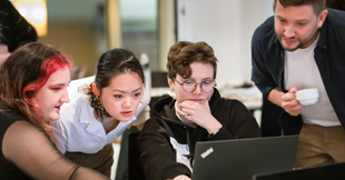 Personen beugen sich über Laptop