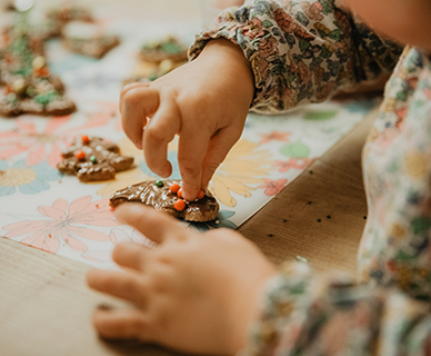 Kleine Kinderhände verzieren frisch gebackene Plätzchen