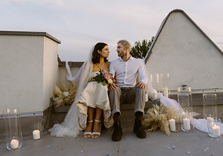 Hochzeitspaar sitzt auf Dachterrasse und schaut sich in die Augen