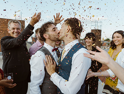 Zwei homosexuelle Männer werden von ihren Freunden beim Hochzeitskussr Hochzeit mit Konfetti beworfen
