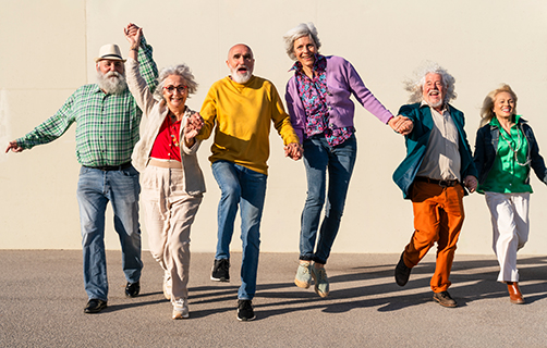 Eine Gruppe von  Senioren läuft lachend und dynamisch auf die Kamera zu