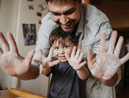 Vater und Sohn halten ihre mehligen Hände in die Kamera 