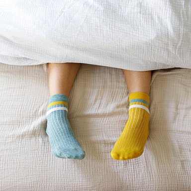 gelbe und blaue Socke schauen unter Decke hervor