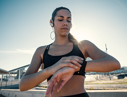 Junge Frau beim Sport schaut auf ihren Fitness-Tracker
