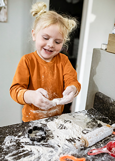 Kleines Mädchen fröhlich beim Plätzchenbacken 