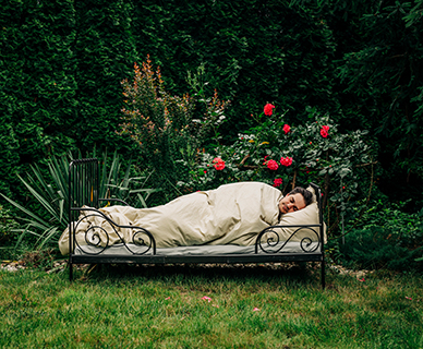 Mann schläft in einem Bett in einem Garten
