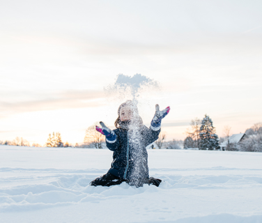 Cute boy playing with snow in winter