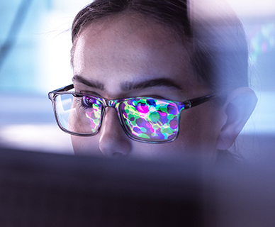 Junge Wissenschaftlerin untersucht Molekularstruktur am Computer, die sich in ihrer Brille spiegelt