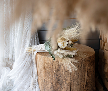 Hochzeitsstrauß oder Deko aus Trockenblumen liegt auf einem Baumstumpf