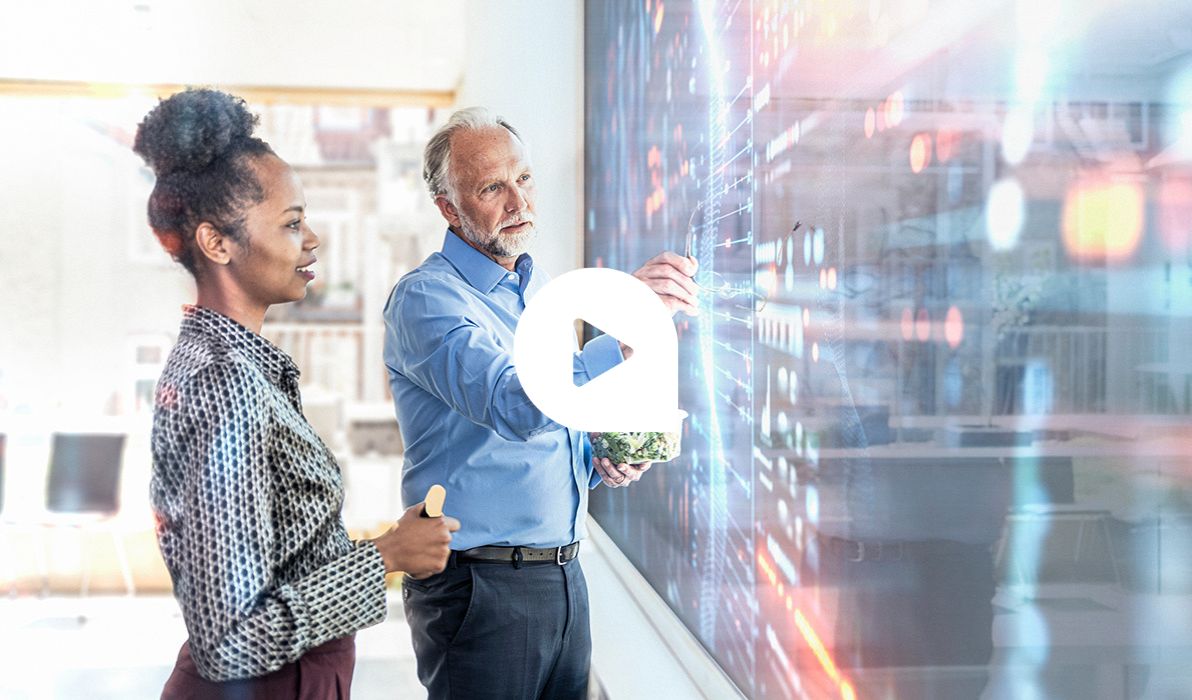 Zwei Fachleute, die mit Augmented Reality arbeiten, besprechen sich vor einem großen Screen