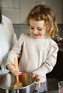 Kleines Mädchen rührt Teig in einer großen Schüssel